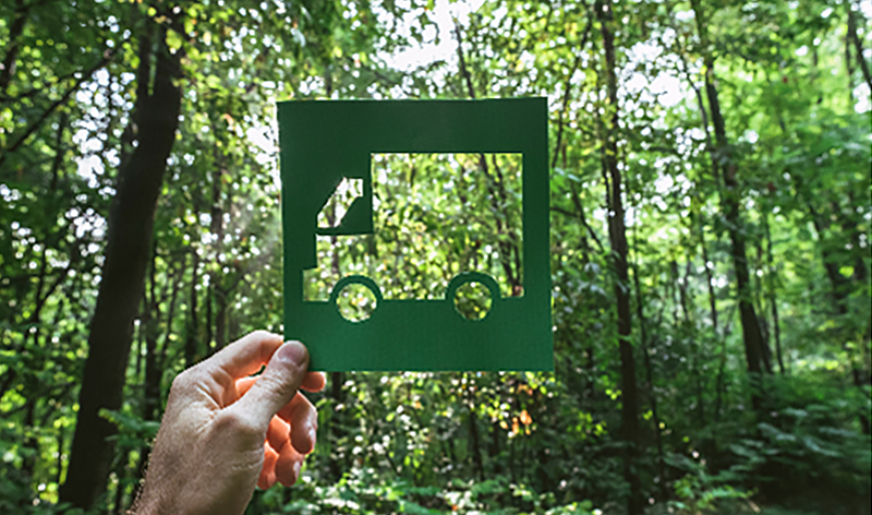 Cary Group, som også omfatter Dansk Busglas, har forpligtet sig til at sætte sine emissionsreduktionsmål En person holder en stencil op i form af en lastbil med skoven som baggrund